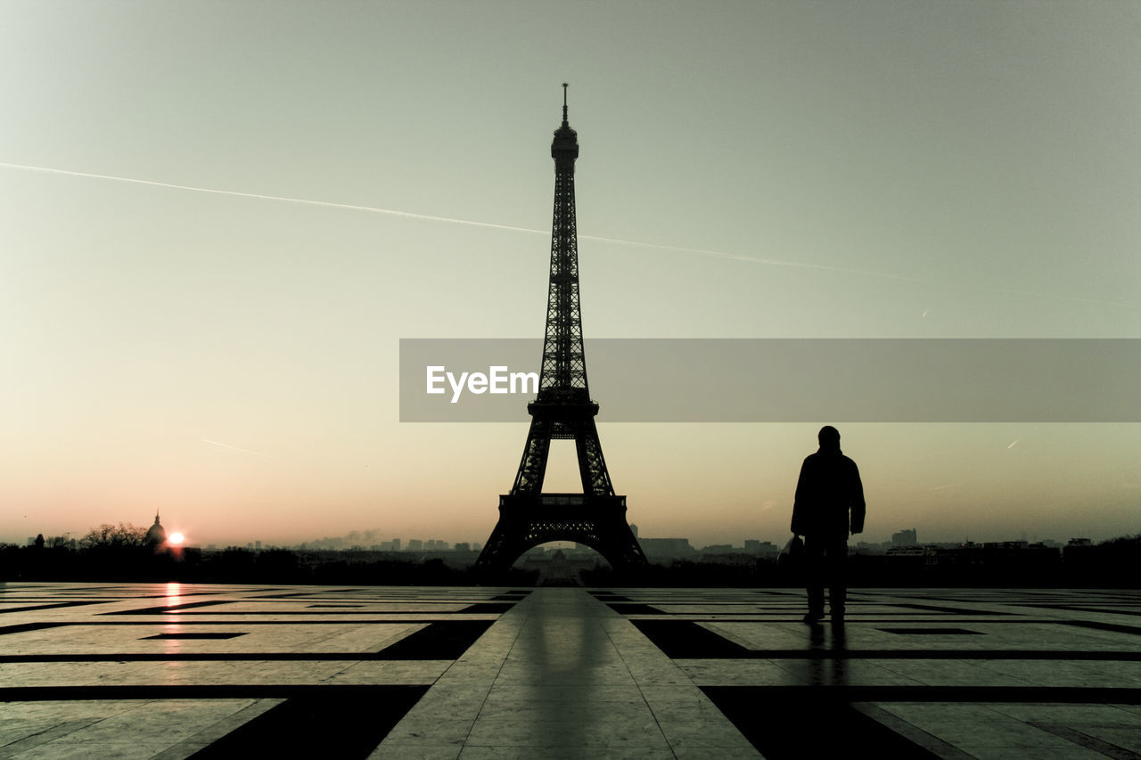 Silhouette man with eiffel tower against sky during sunset