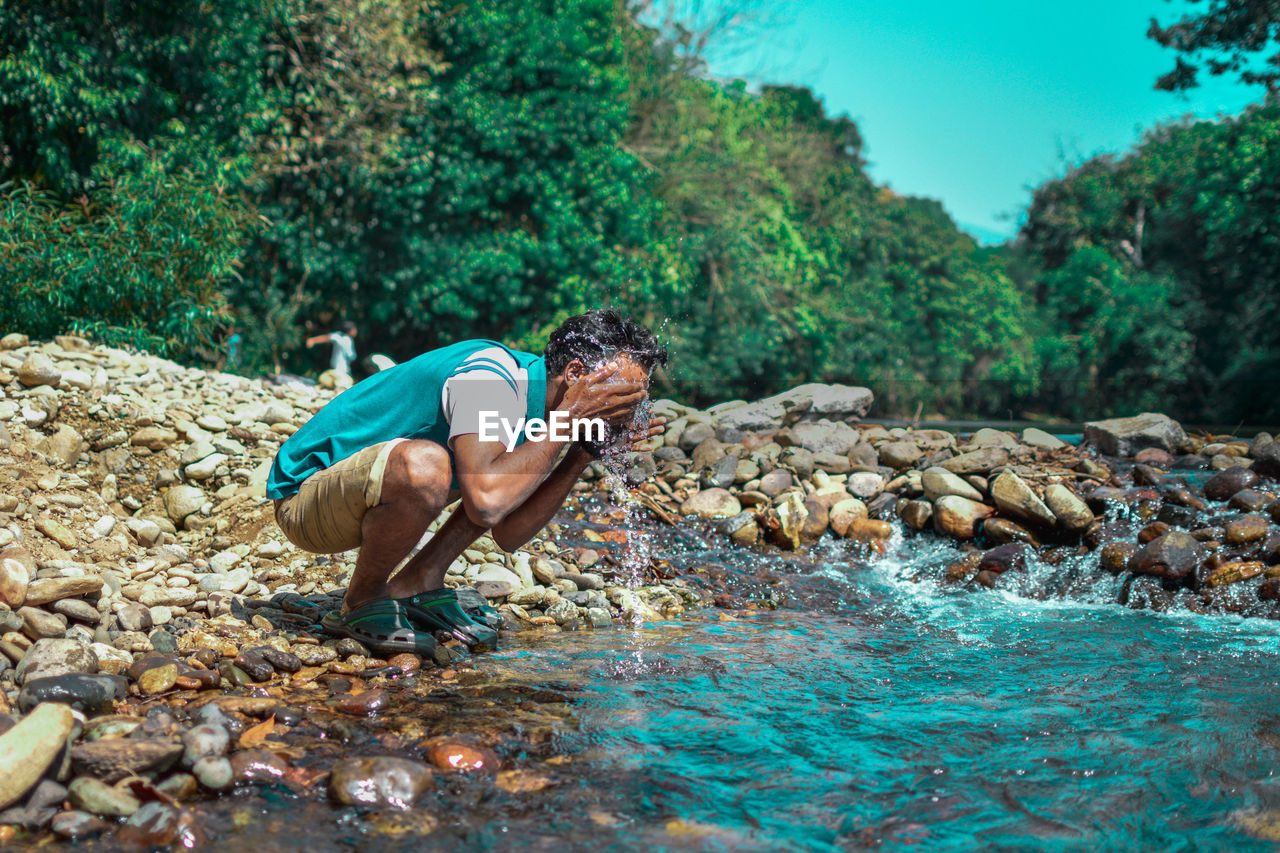 SIDE VIEW OF MAN SURFING IN WATER