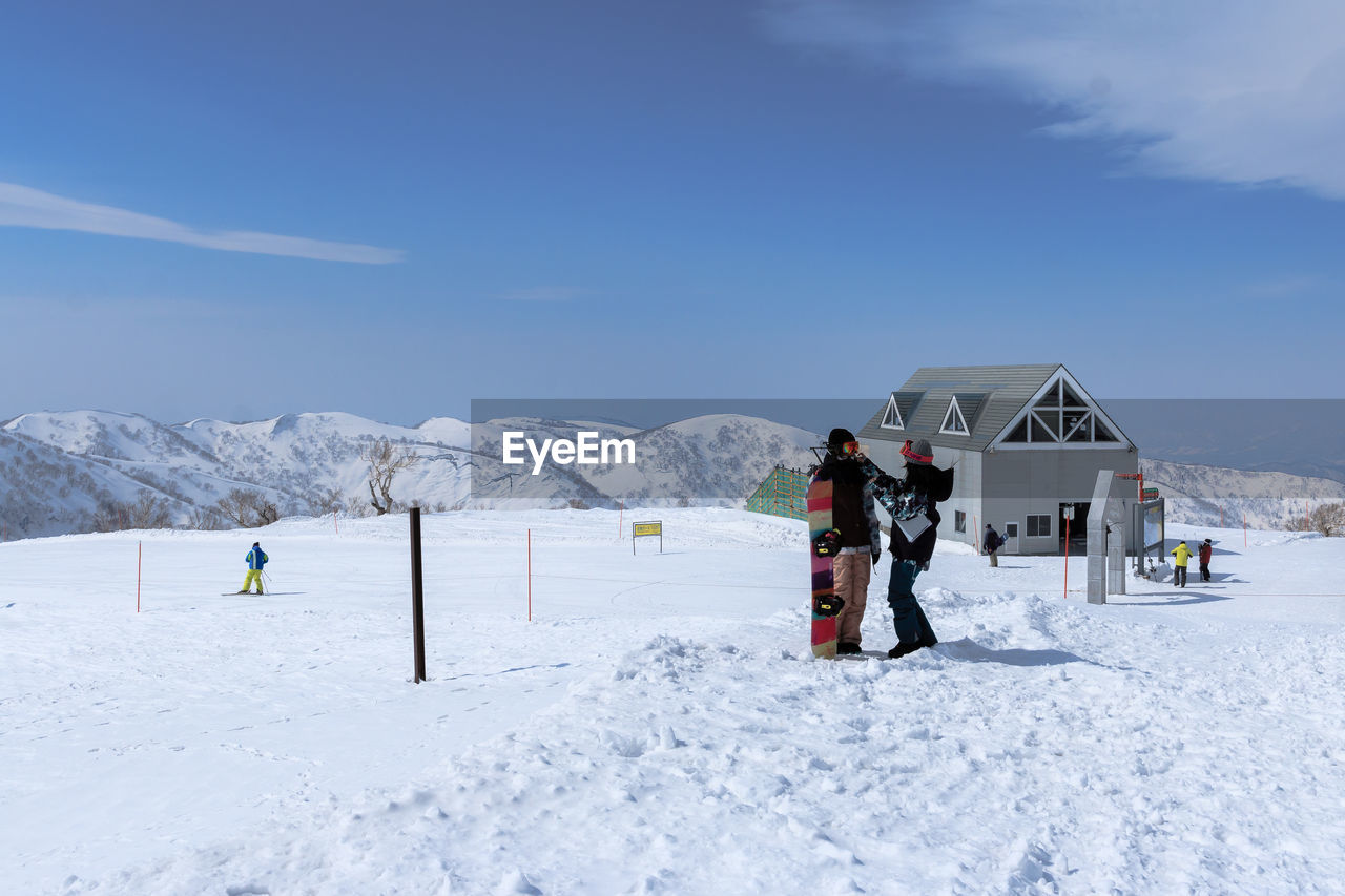 PEOPLE WALKING ON SNOWCAPPED MOUNTAINS AGAINST SKY