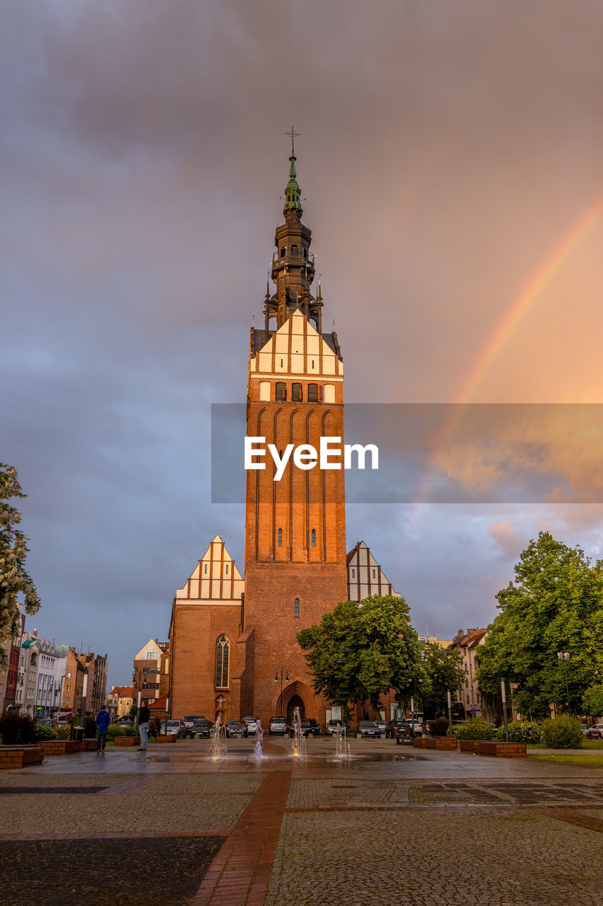 Church tower amidst buildings against sky during sunset in the city elblag.