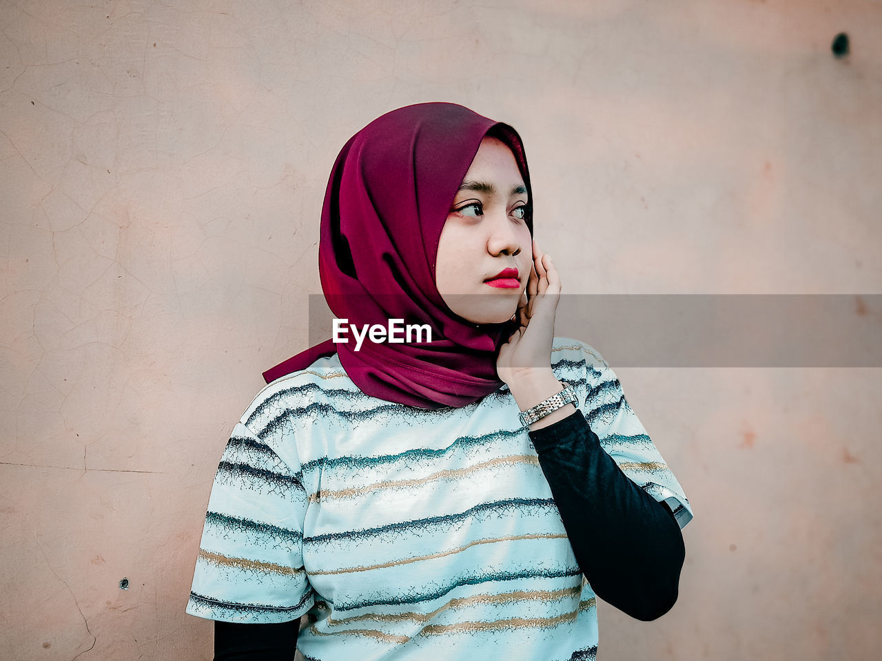 Portrait of young woman standing against wall