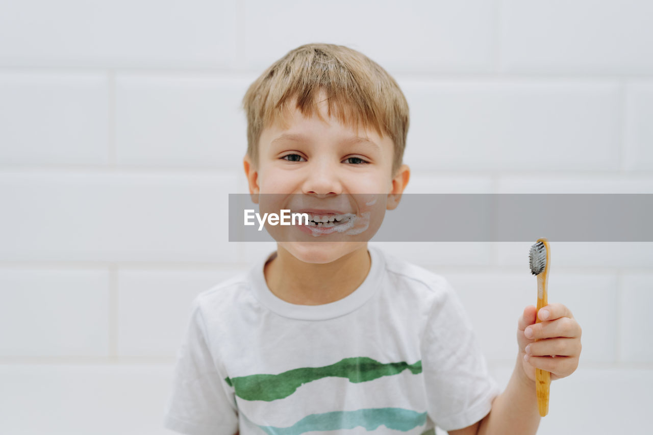 Cute 5 years old boy brushing teeth with bamboo tooth brush in bathroom. image with selective focus