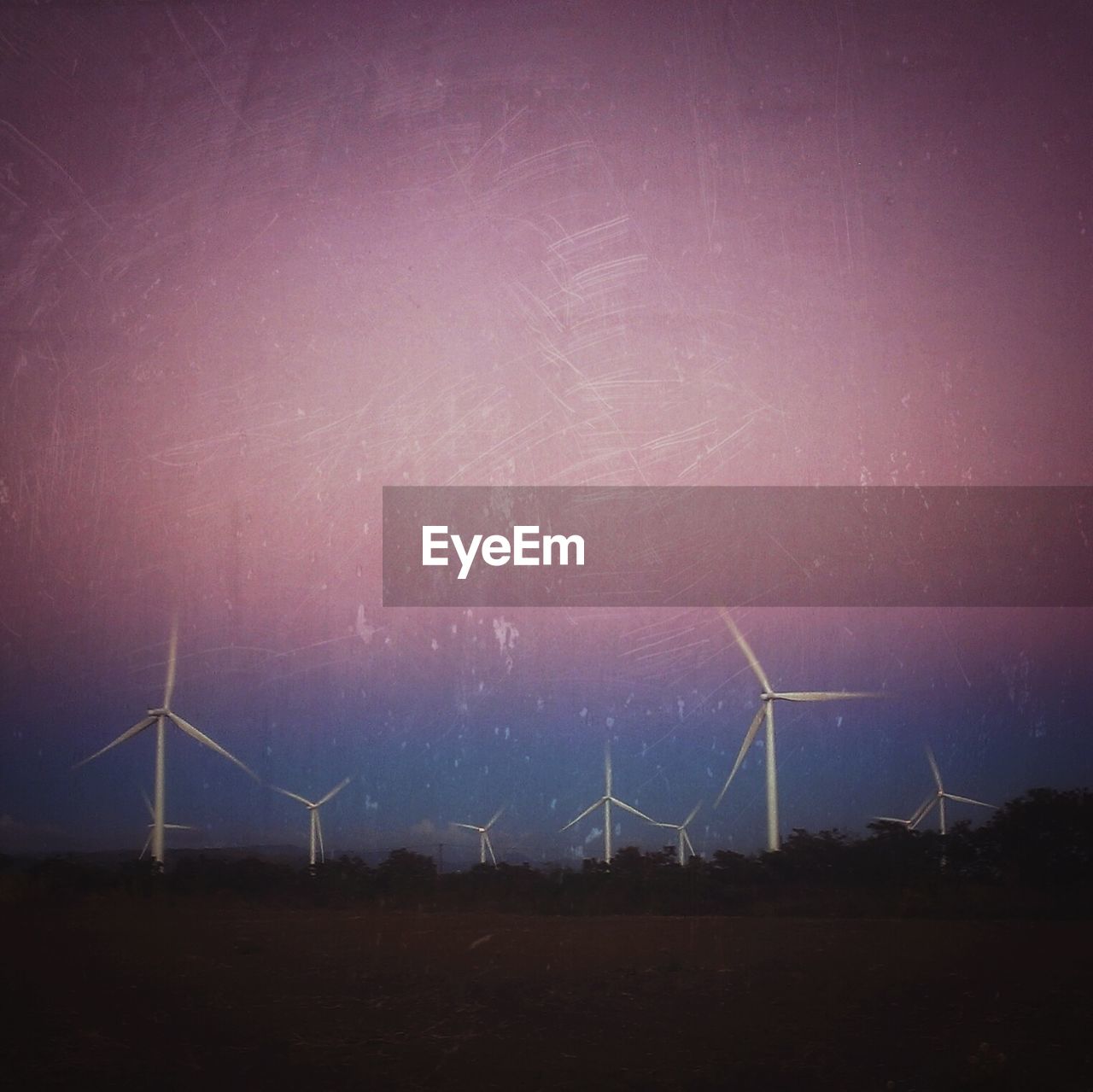 Windmill on field against sky at dusk