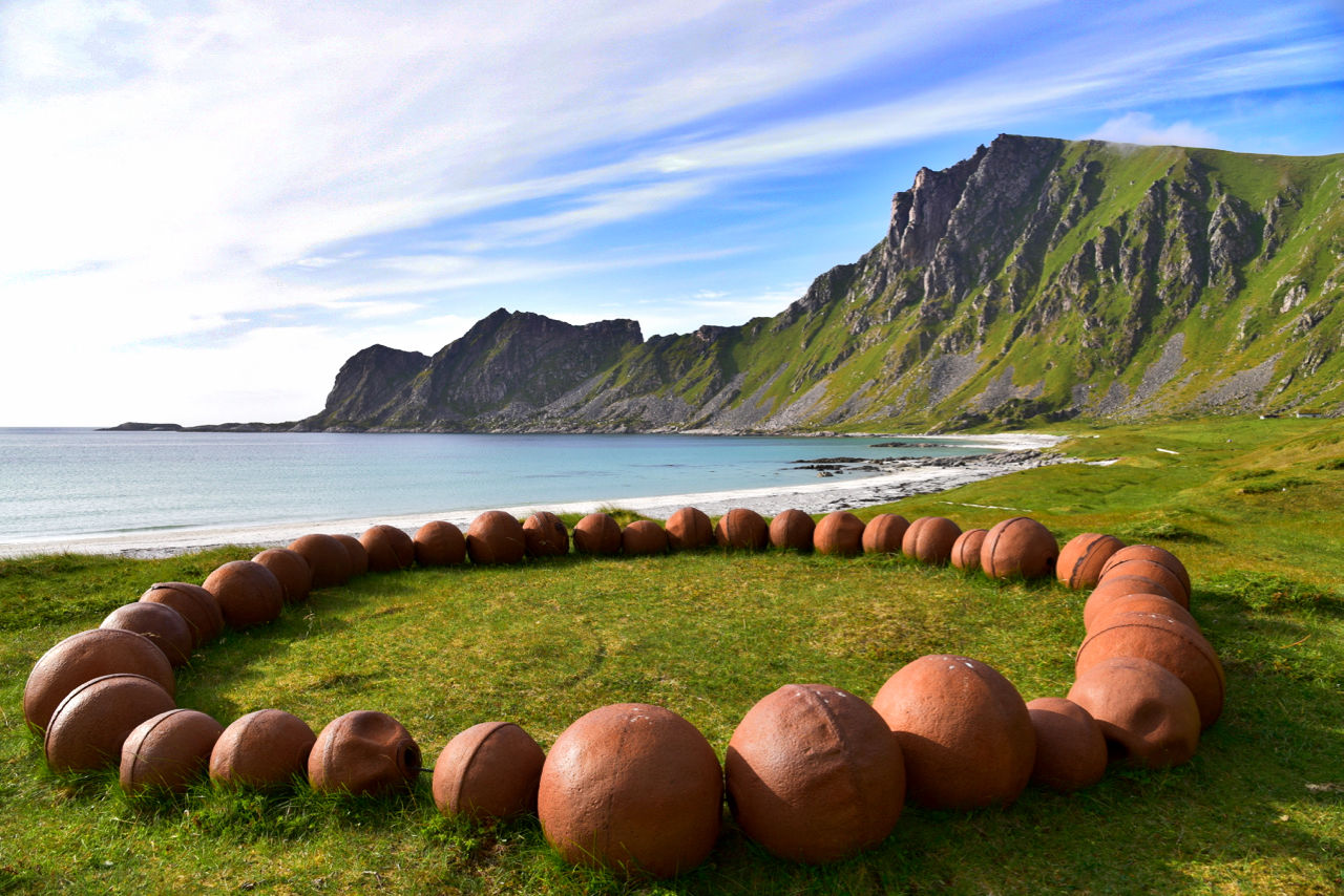 Buoy arranged on grassy beach against sky