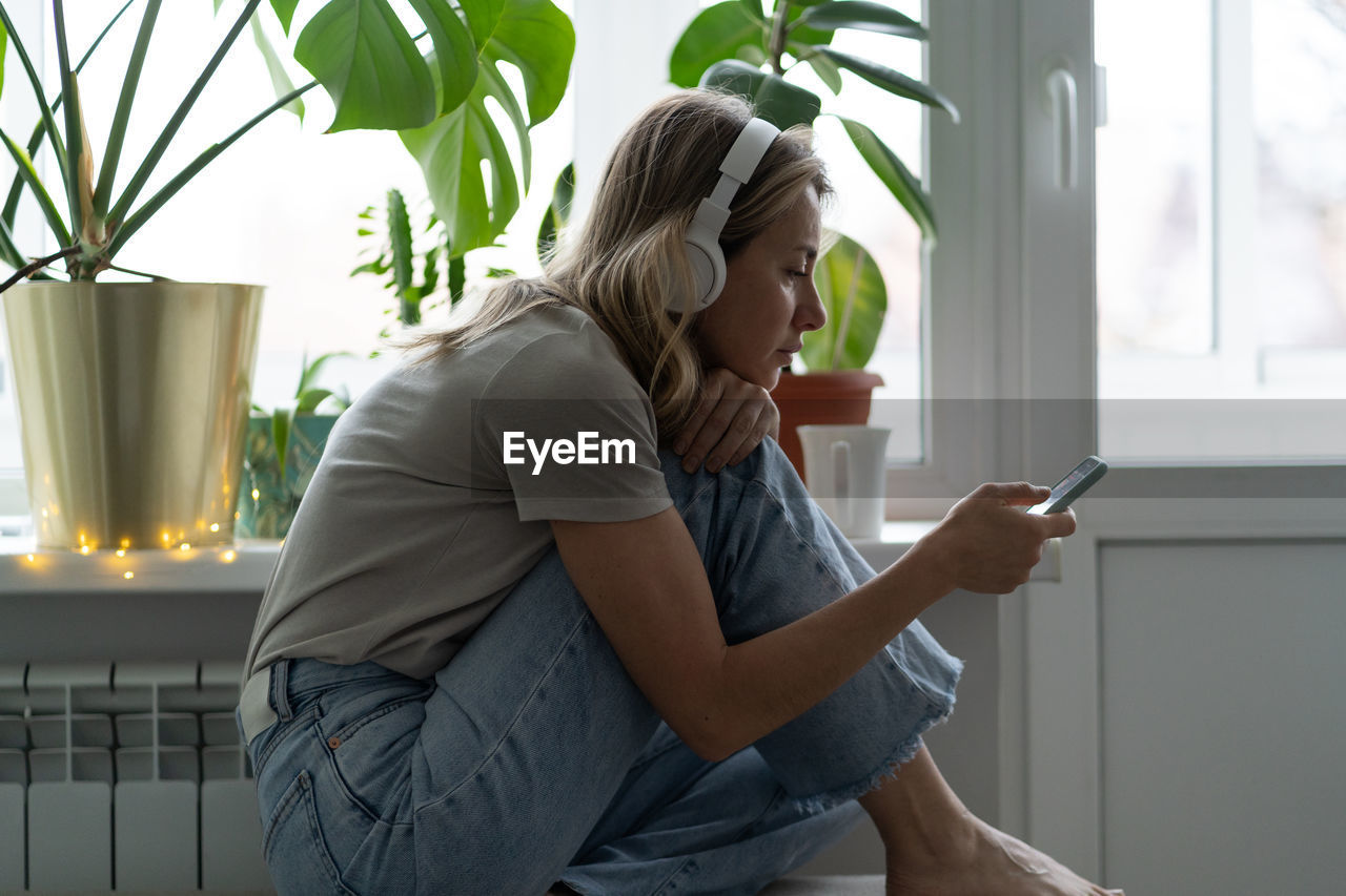 Woman listening music over mobile phone at home