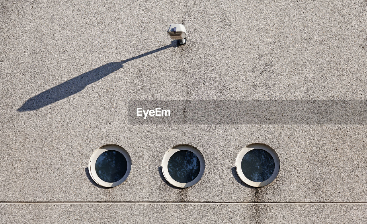 Concrete wall with three round windows and with a lamp above