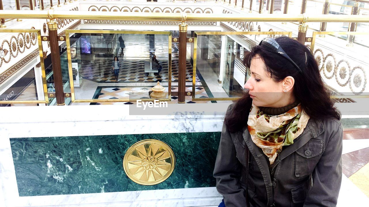 Young woman sitting on marble bench at shopping mall