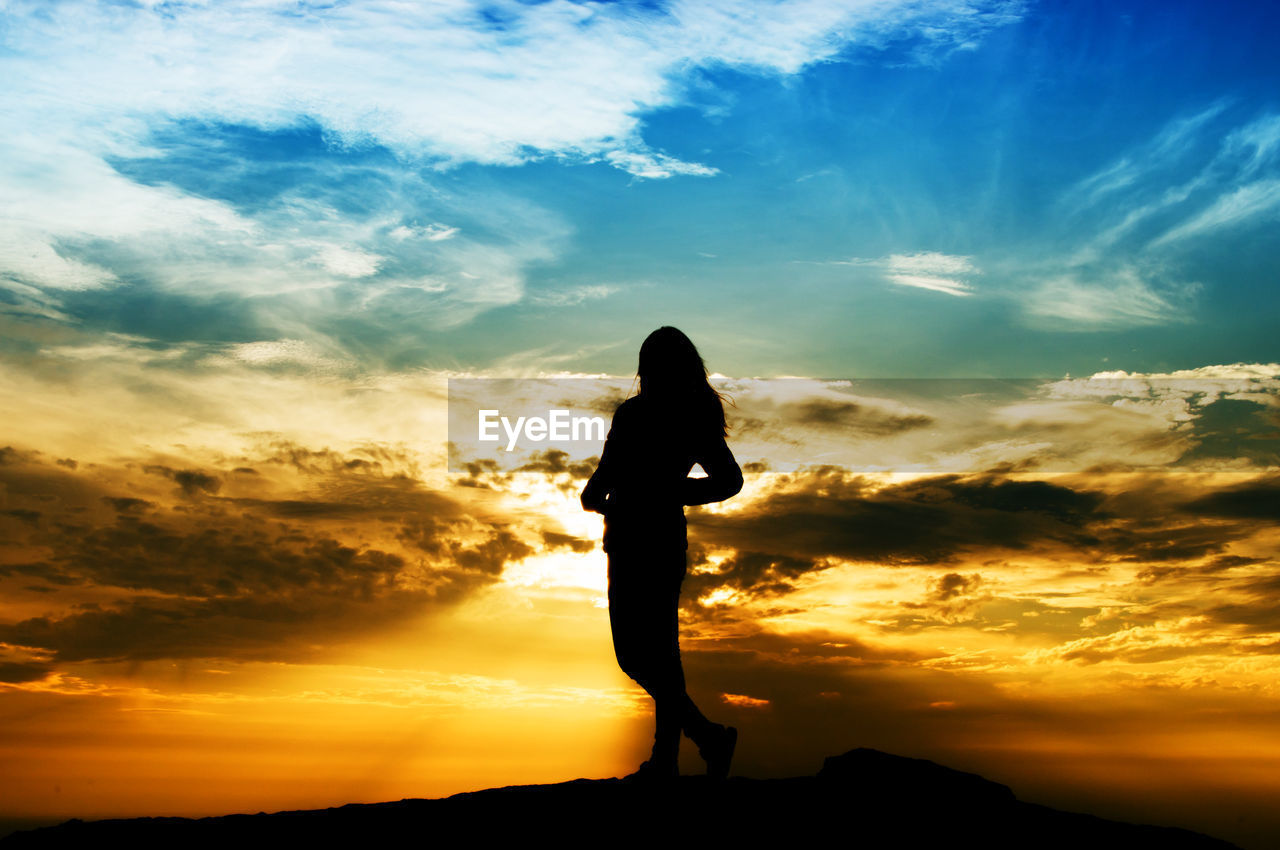 Silhouette woman standing on mountain against sky during sunset