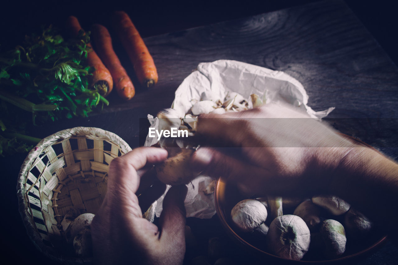 Cropped image of chef peeling mushroom on table