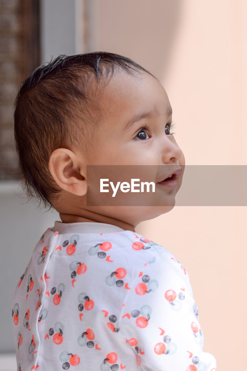 Close-up of cute baby girl looking away