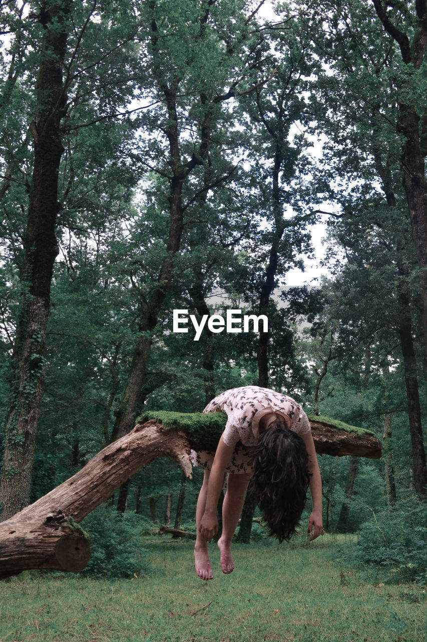 Woman hanging on fallen tree in forest