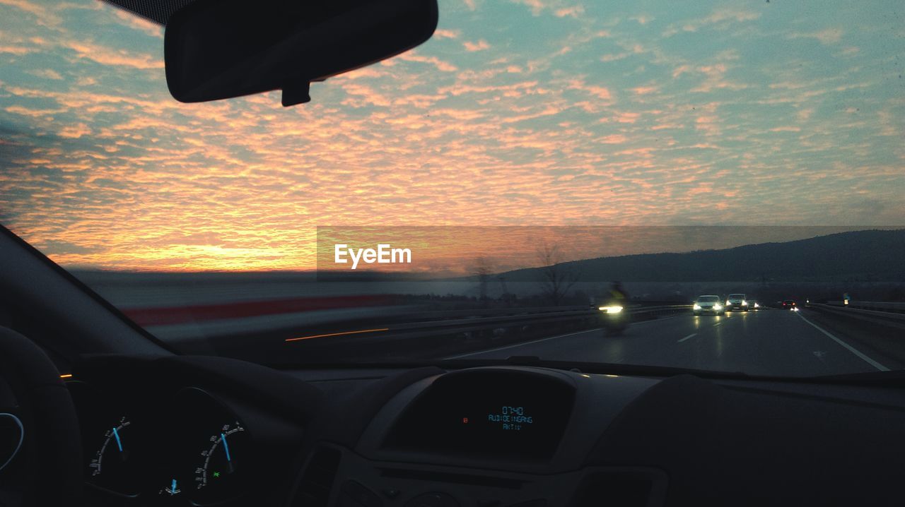 Empty road along countryside landscape at sunset