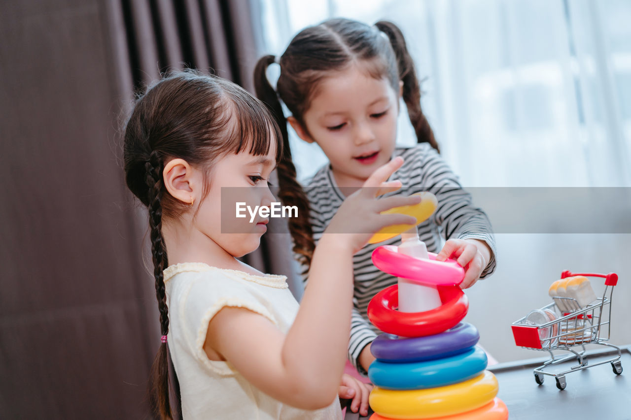 Sisters playing with multi colored toys at home