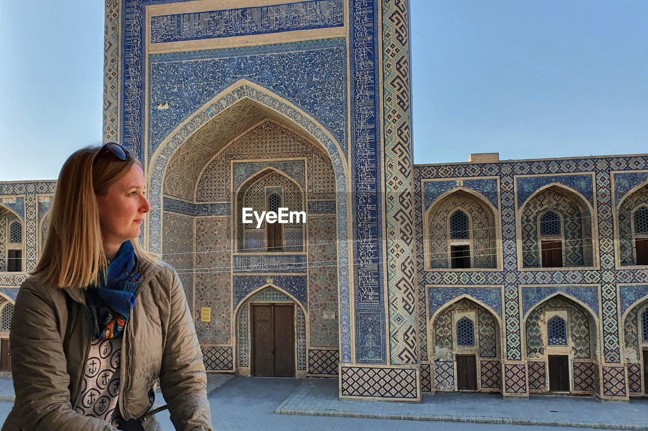 Portrait of blond girl in front of blue madrasa