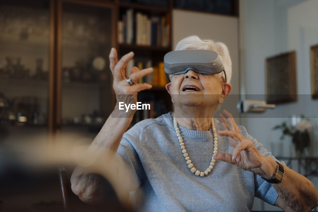 Senior woman wearing virtual reality simulator sitting at home