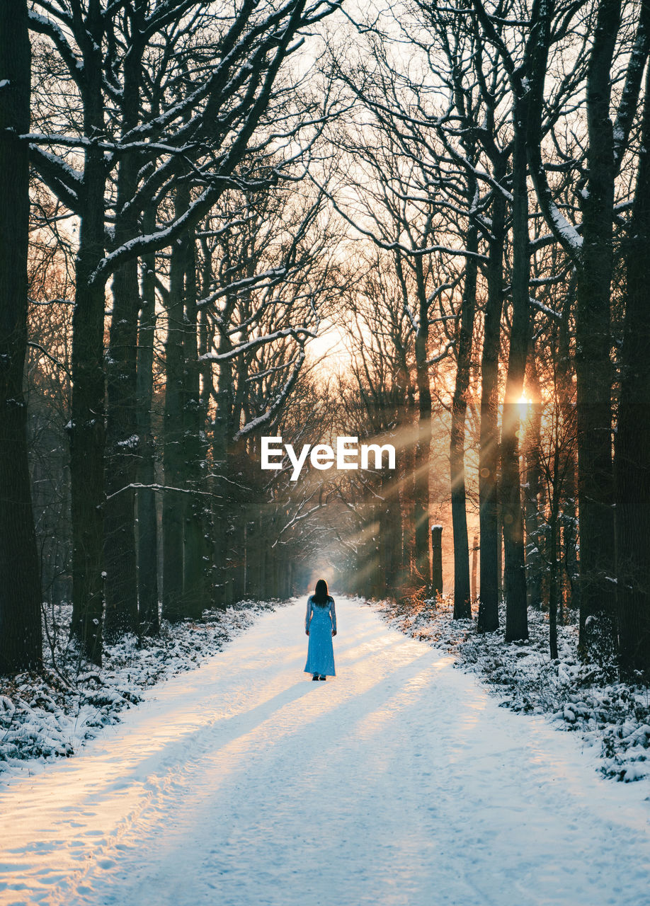 rear view of woman walking on snow covered landscape