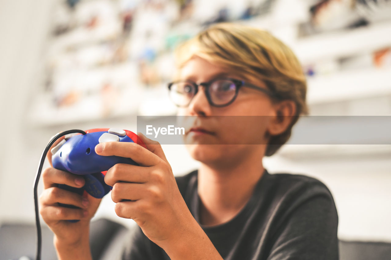 Close-up of boy playing video game at home