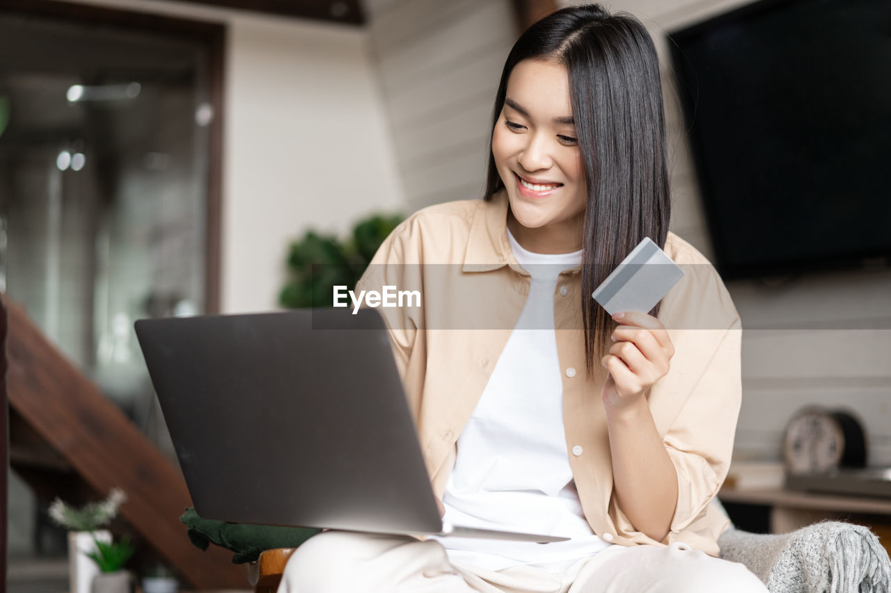 young woman using mobile phone while sitting at home