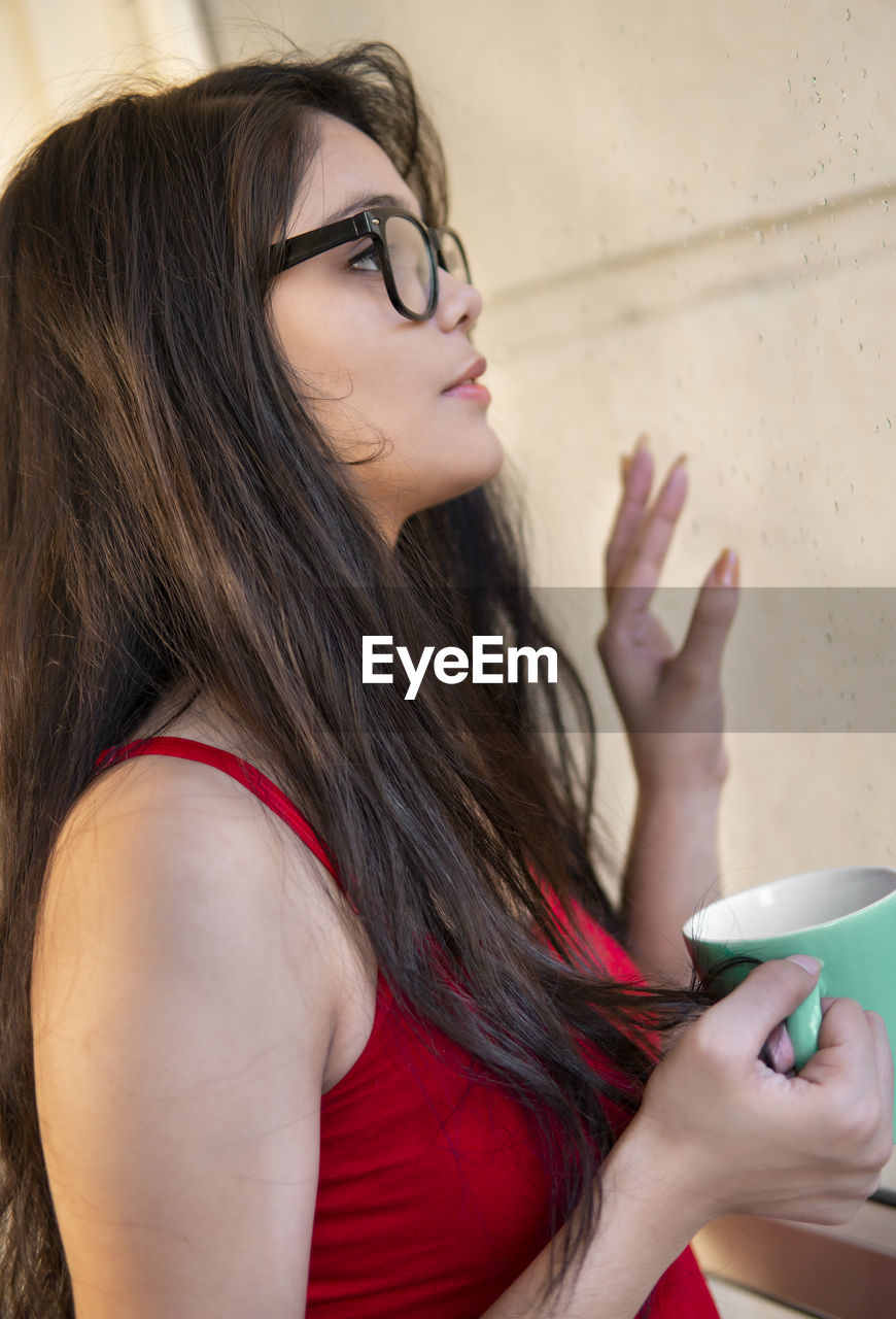 Young woman holding cup while looking away