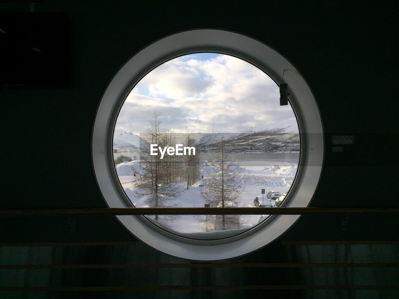 Scenic view of snow covered land and sky seen through glass window