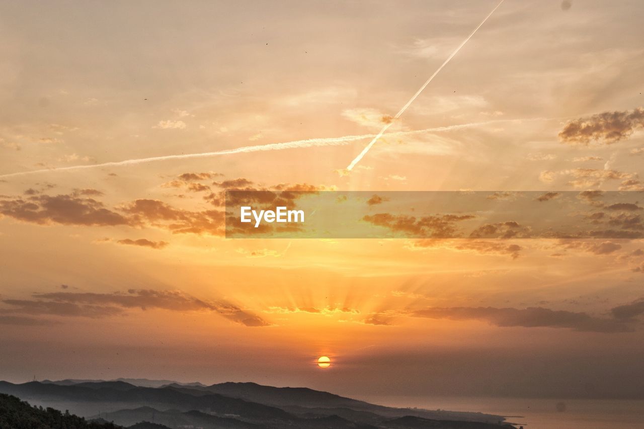 SCENIC VIEW OF VAPOR TRAILS IN SKY DURING SUNSET