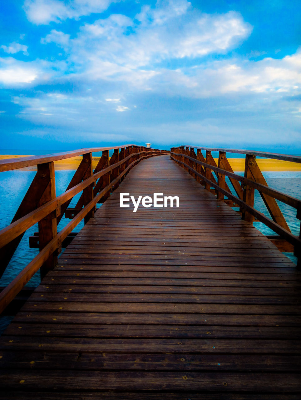 sky, water, wood, cloud, sea, sunlight, blue, nature, the way forward, pier, horizon, land, boardwalk, reflection, architecture, beach, scenics - nature, tranquility, bridge, beauty in nature, jetty, no people, travel destinations, footpath, diminishing perspective, tranquil scene, ocean, dusk, horizon over water, walkway, environment, landscape, outdoors, holiday, built structure, evening, travel, railing, trip, transportation, vacation, sunset, footbridge, tourism, idyllic, vanishing point, seascape, long, summer, urban skyline