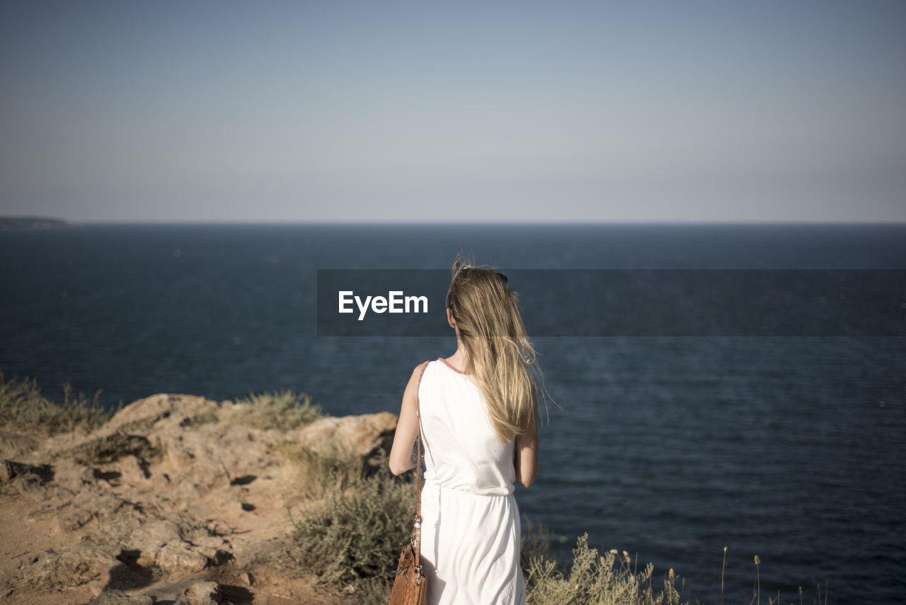 Rear view of woman standing in front of sea