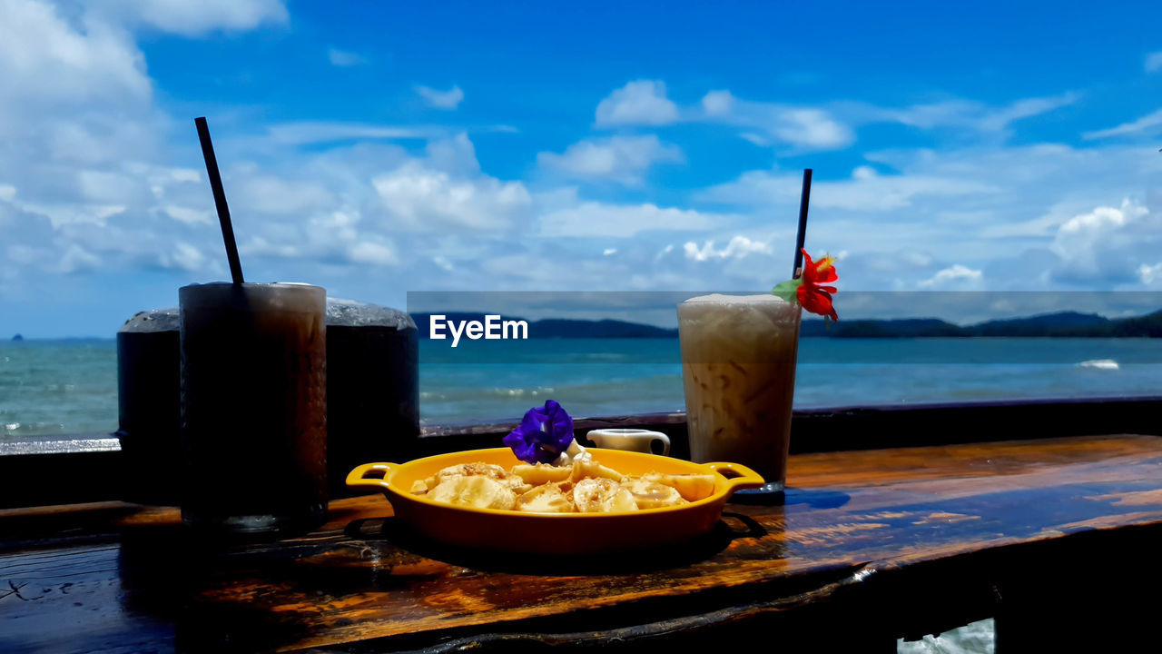 VIEW OF DRINK ON TABLE AGAINST SEA