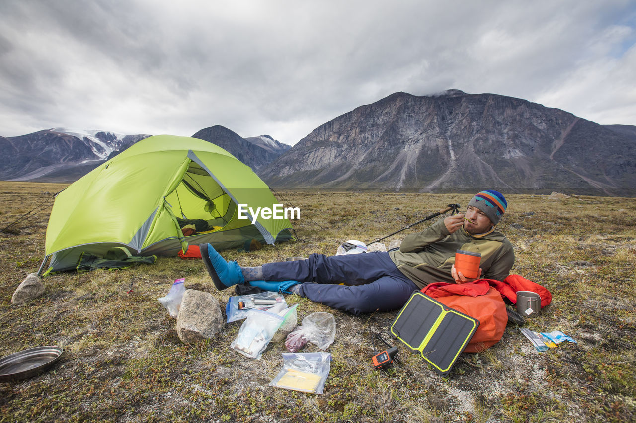 Climber eats meal, relaxes, charges devices at campsite.