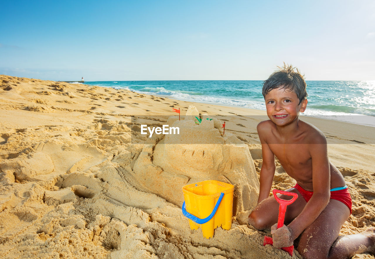 high angle view of boy playing at beach against clear sky