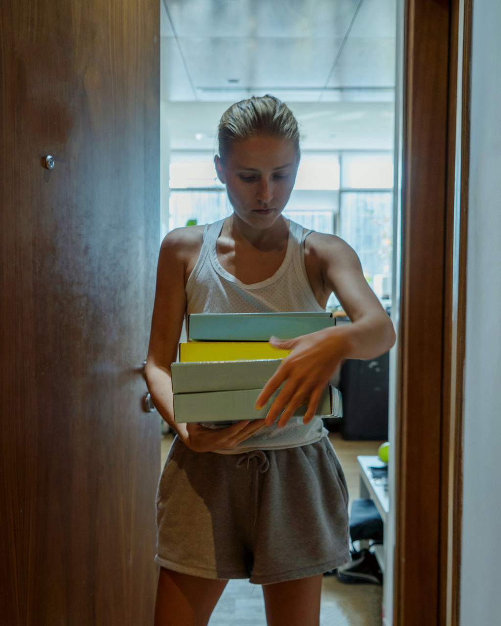 Portrait of a young woman standing against door with the pizza boxes