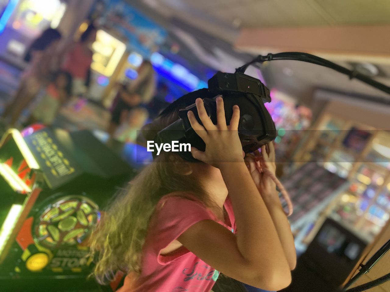 A girl is playing virtual games holding a camera on her head by hands