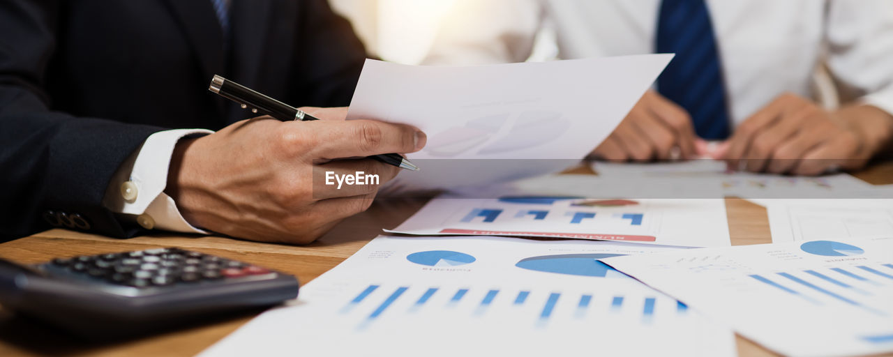 Midsection of business colleagues working on table