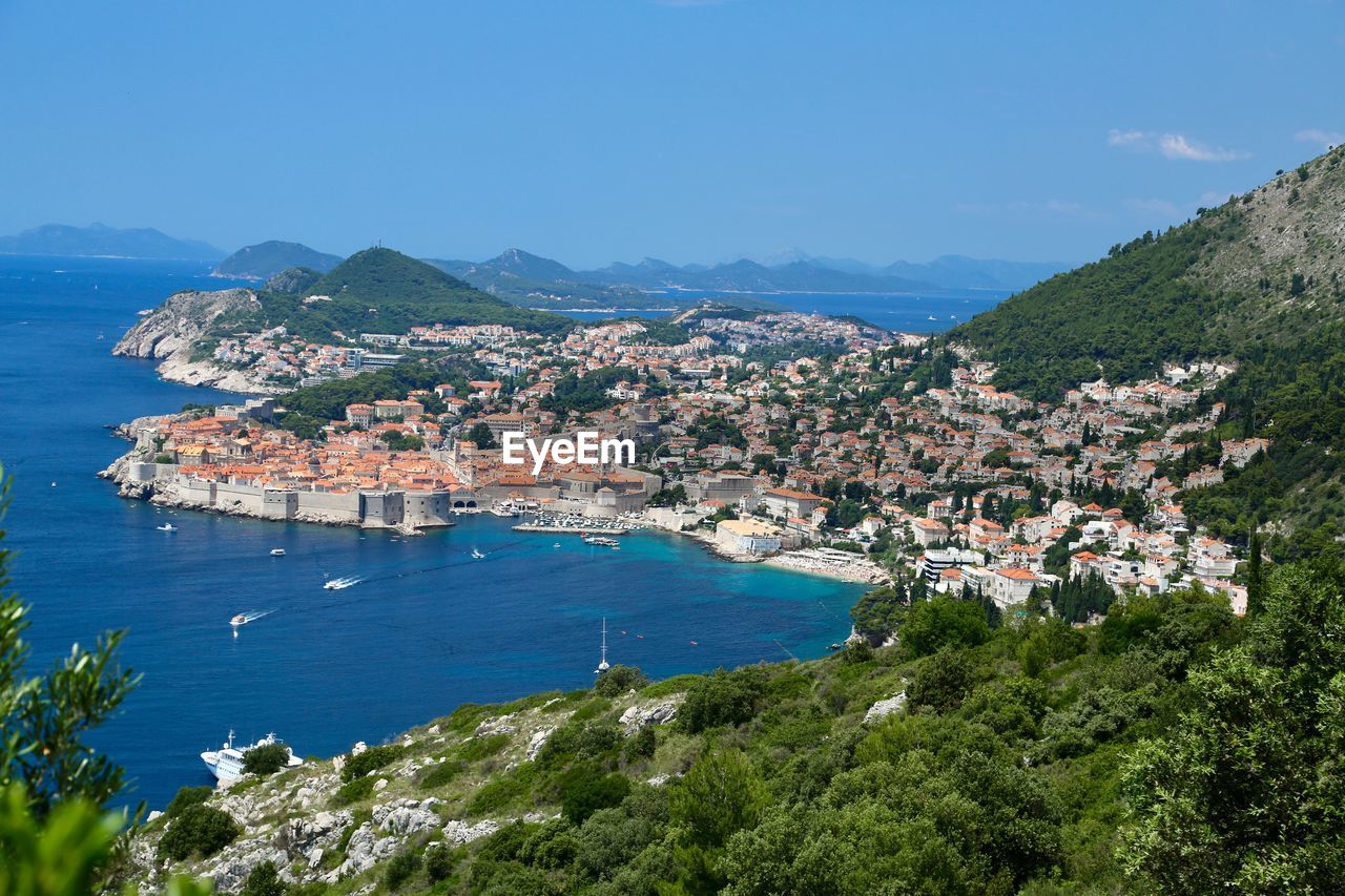Aerial view of townscape by sea against sky