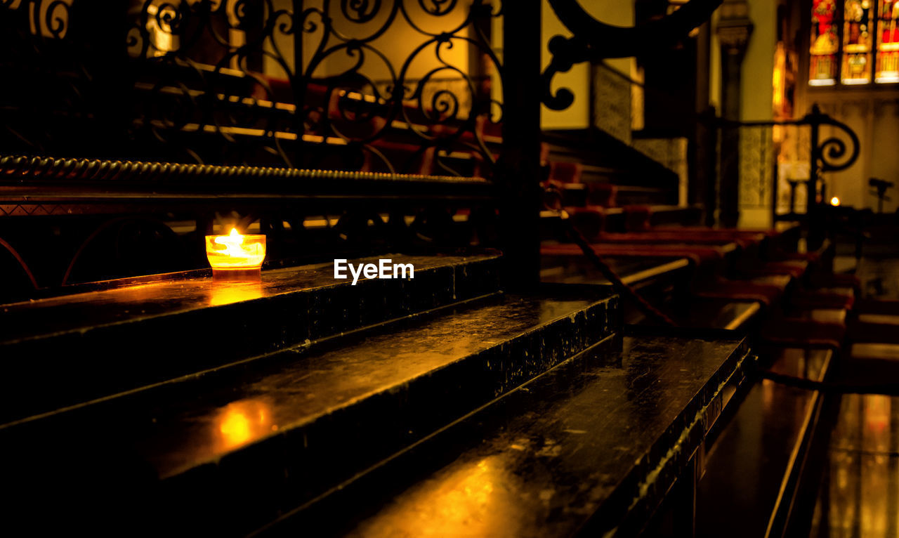 Close-up of illuminated tea light candle on steps in church