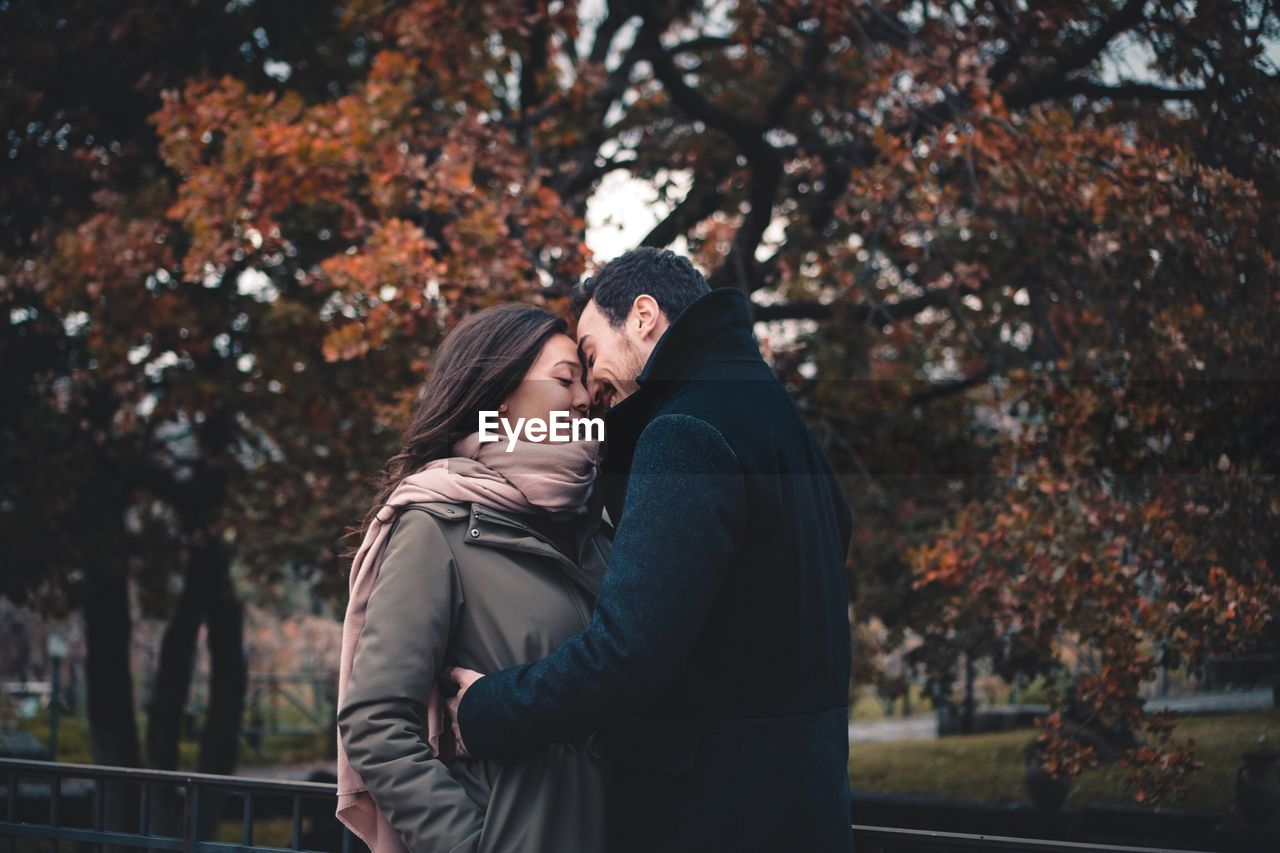 REAR VIEW OF COUPLE KISSING IN PARK