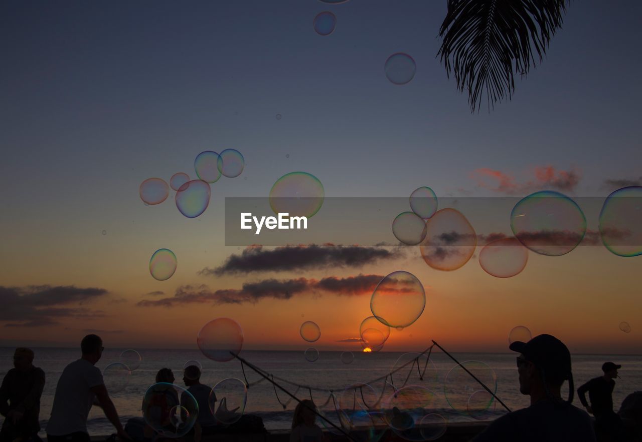 Close-up of bubbles by people at beach during sunset