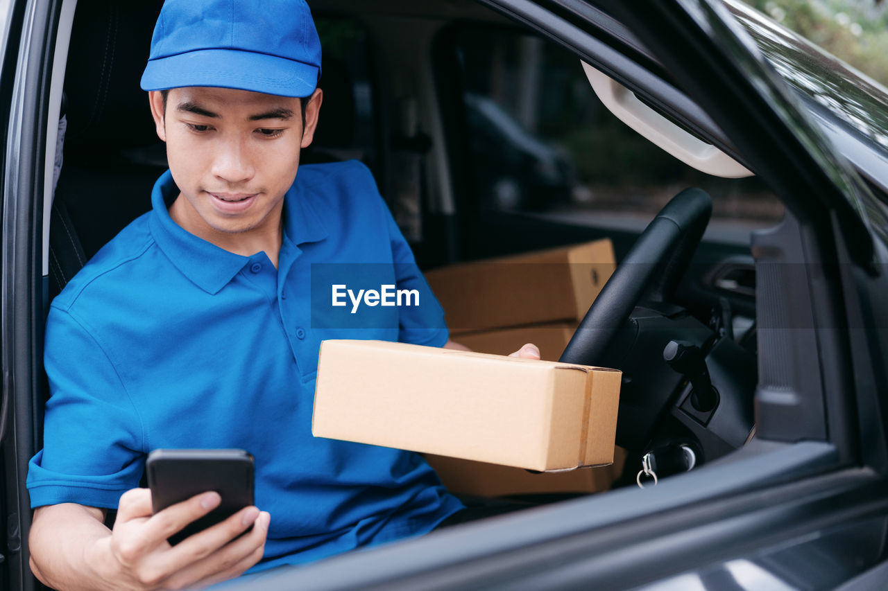 Delivery man holding parcel while sitting in car