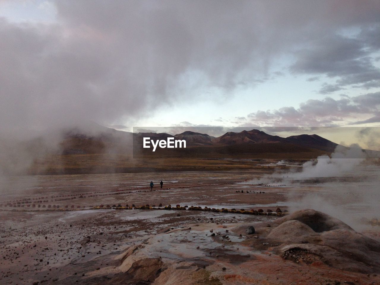 Geyser emitting from volcanic mountain against sky