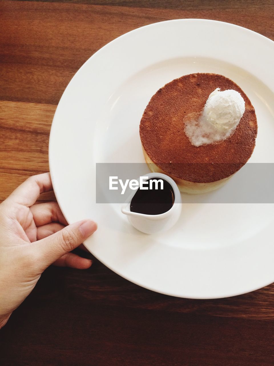 Cropped image of hand holding plate with pancake and coffee cup