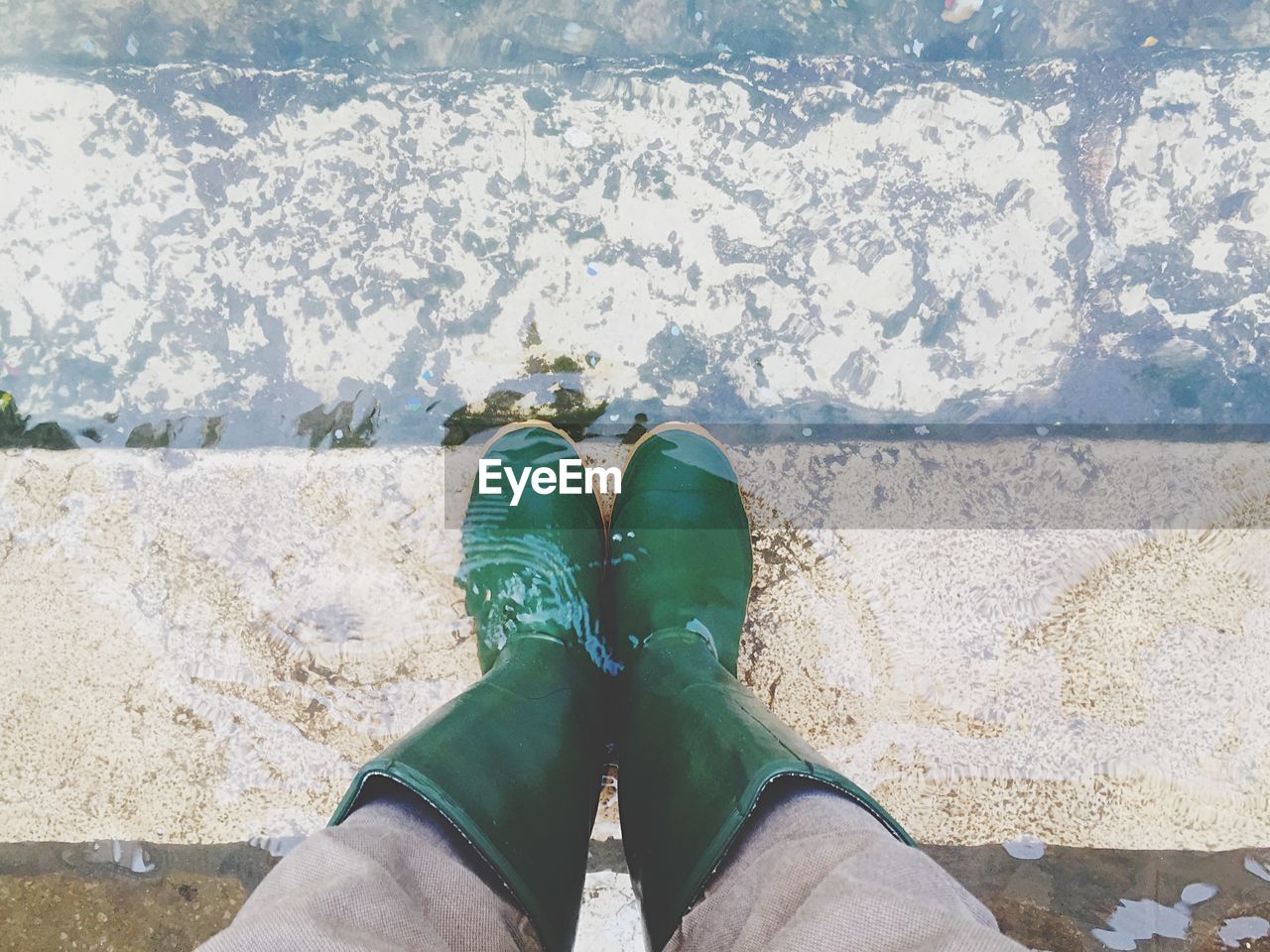 Low section of person standing in water on steps at pond