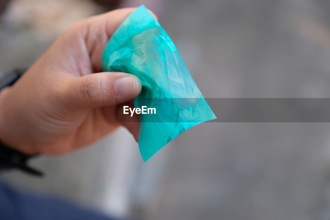 Close-up of human hand holding blue paper