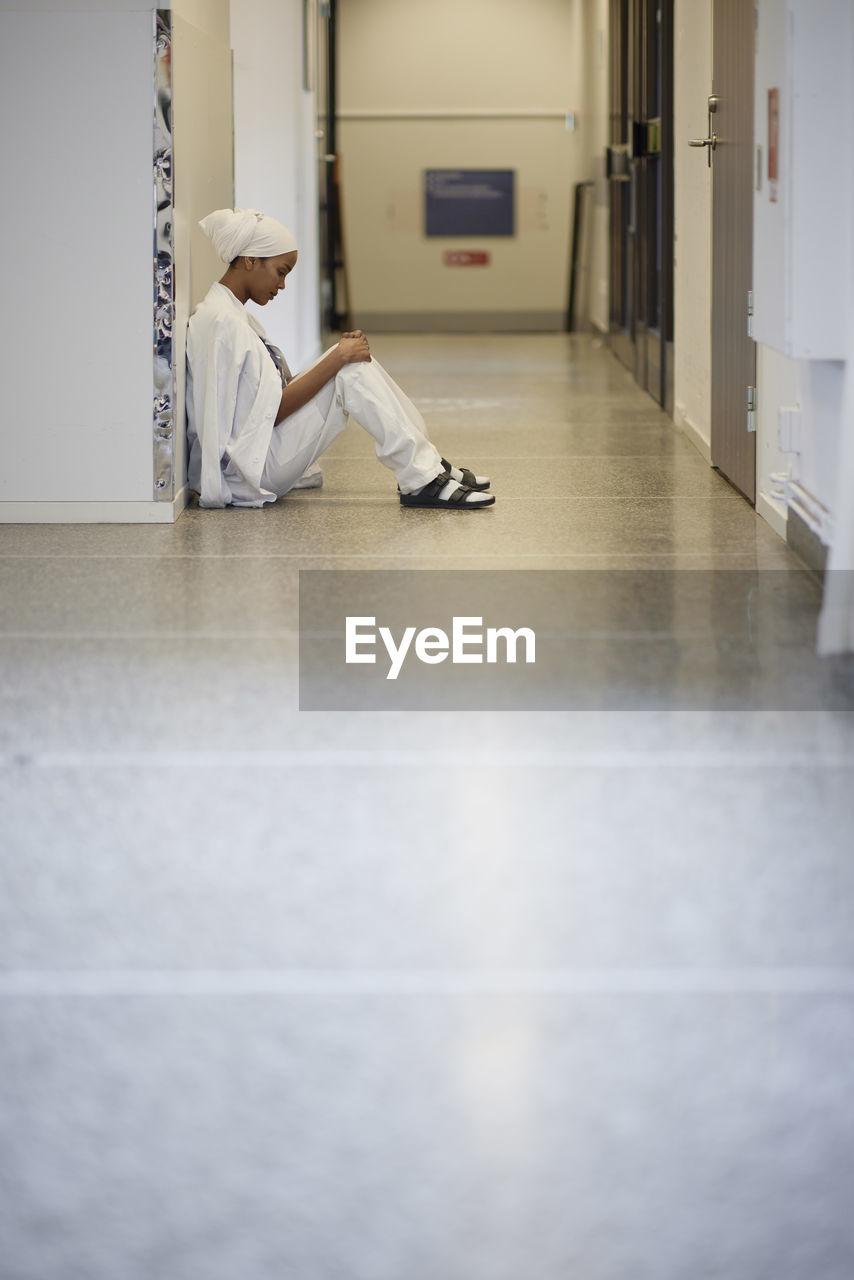 Female doctor sitting on hospital corridor floor