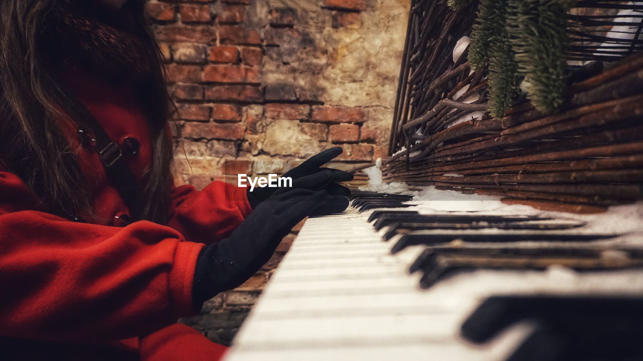 Midsection of woman playing abandoned piano during winter