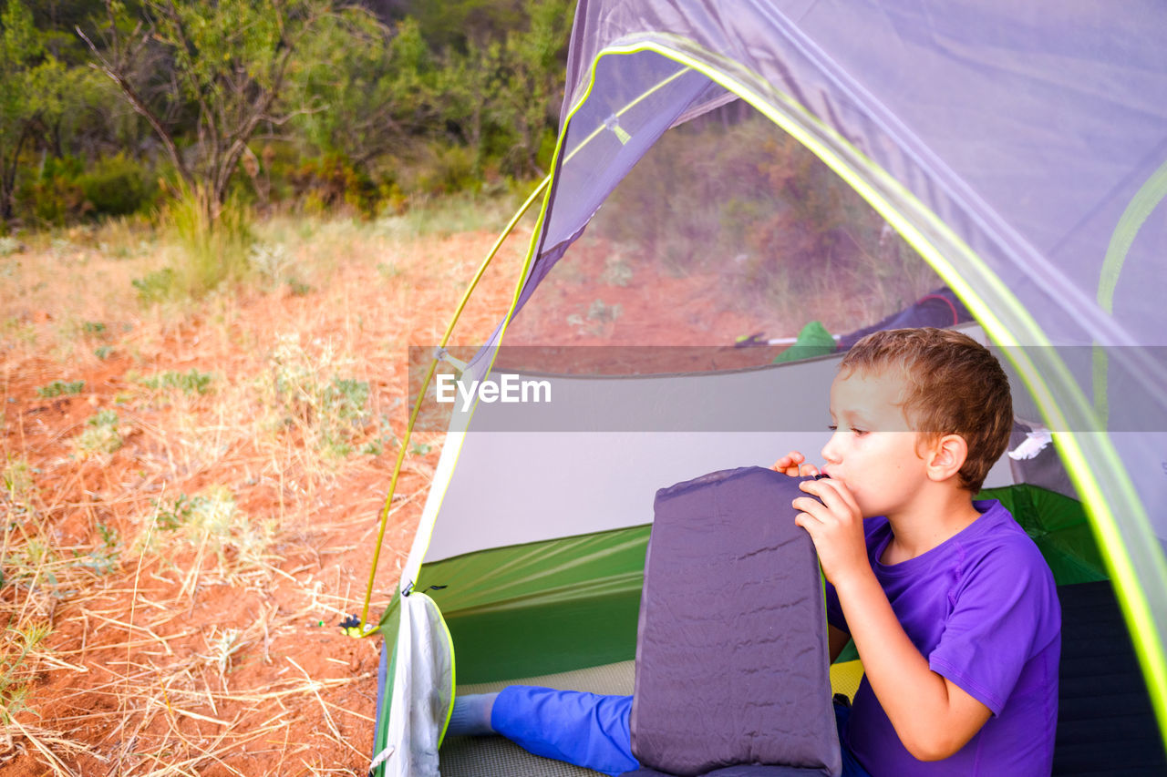 FULL LENGTH OF BOY SITTING AT TENT