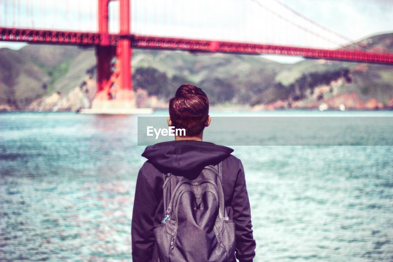 Rear view of man overlooking calm river