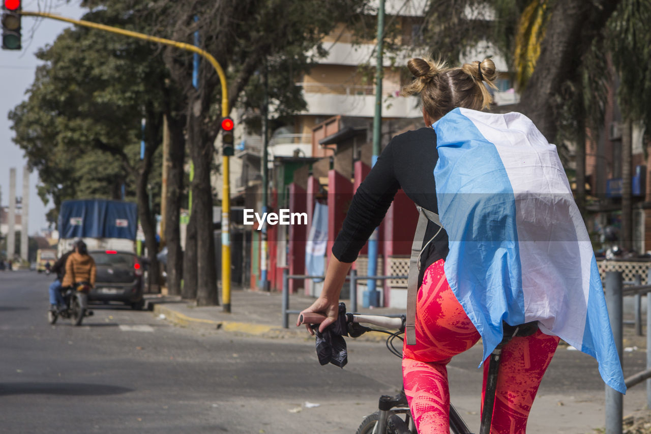 REAR VIEW OF WOMAN ON STREET AGAINST CITY