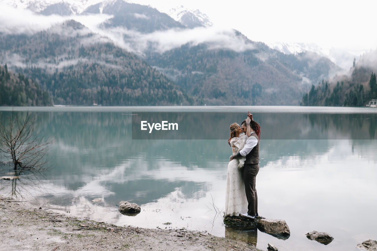 A happy couple in love and married embrace in nature by the lake and the misty mountains