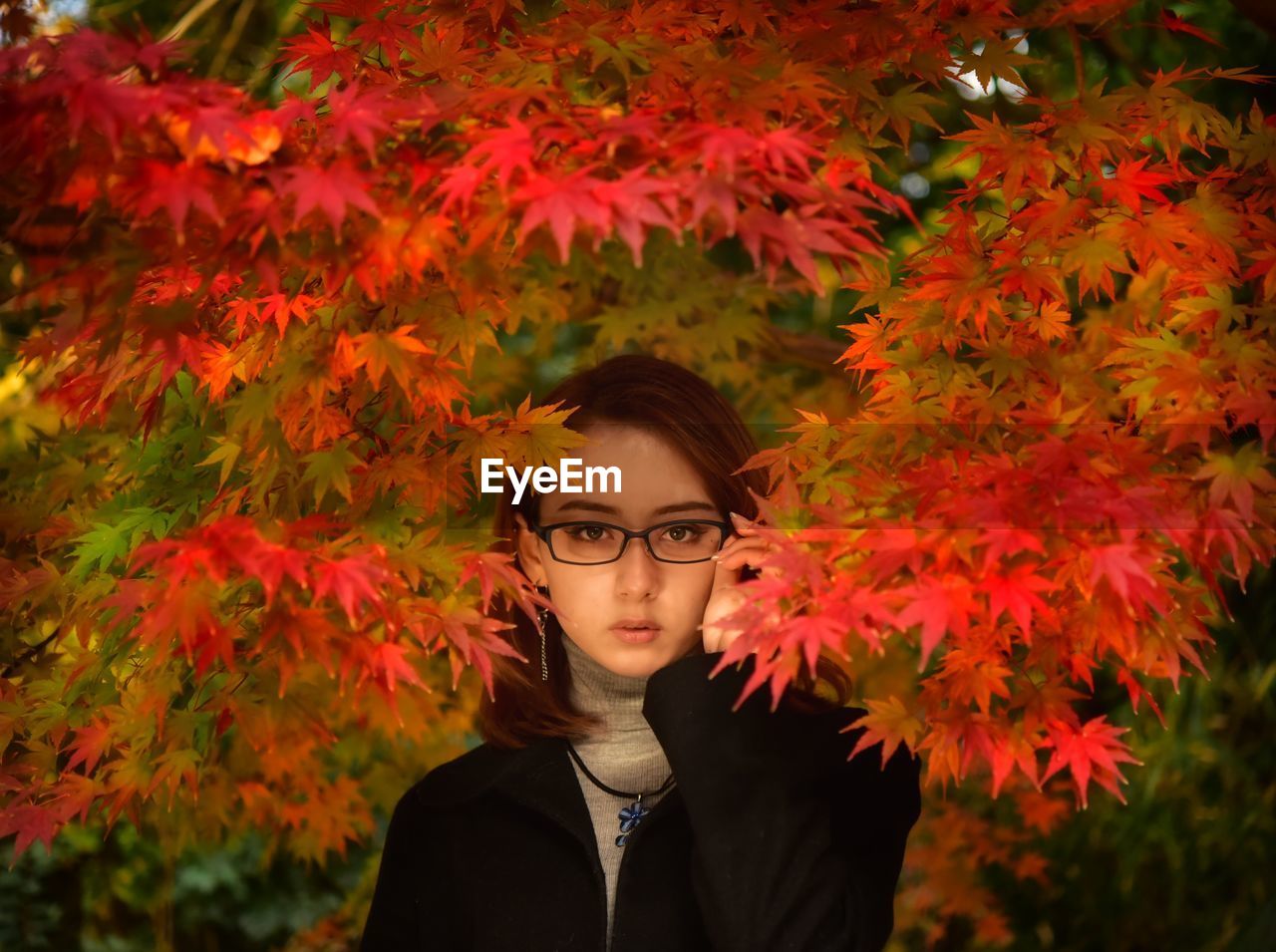 Portrait of young woman standing by plants during autumn