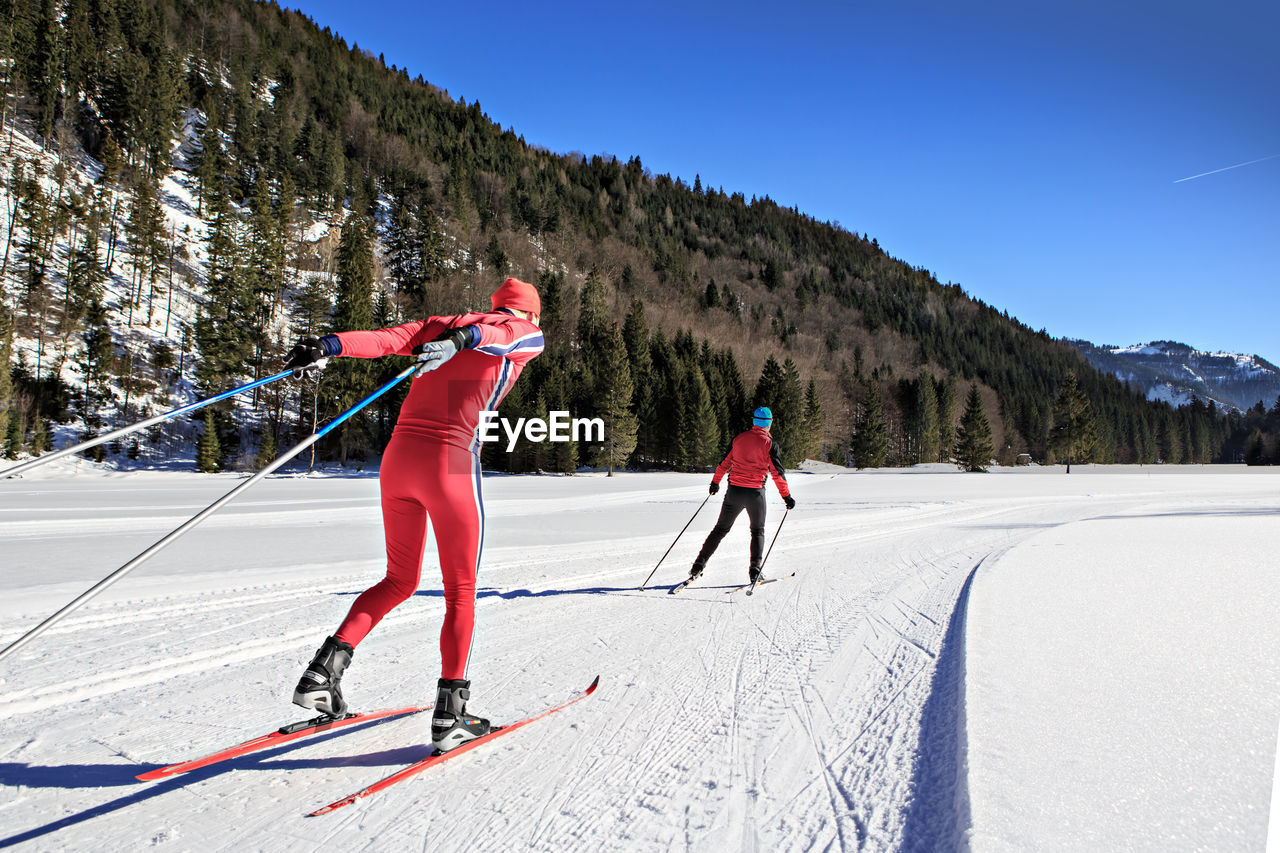 Rear view of men skiing on field against mountain